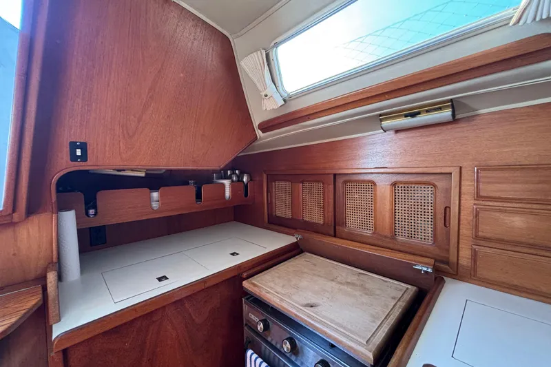 Slide: The Image of Interior of 1979 Islander Peterson 40 sailboat, featuring a wooden galley with stove and storage. - 45
