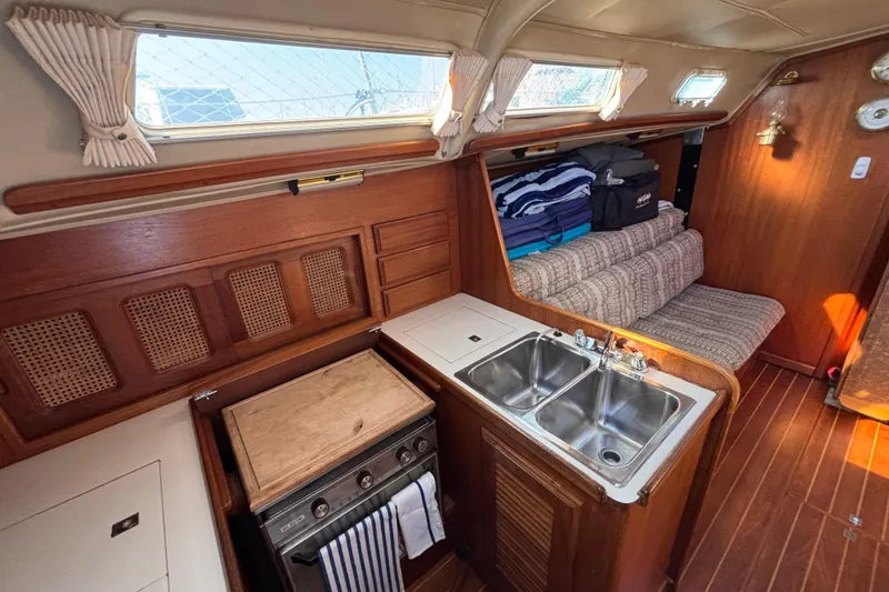 Slide: The Image of Interior of 1979 Islander Peterson 40 sailboat with wood finish, kitchenette, and seating area. - 46