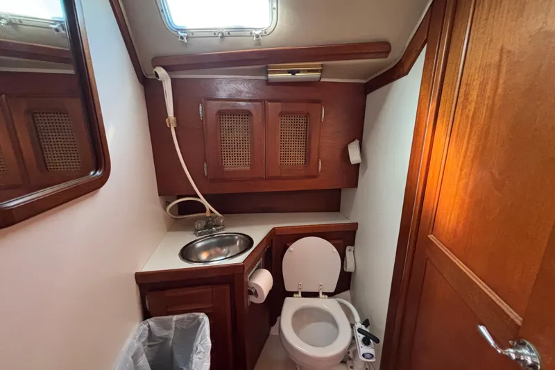 Slide: The Image of 1979 Islander Peterson 40 yacht bathroom with wooden cabinets, sink, and toilet. - 51
