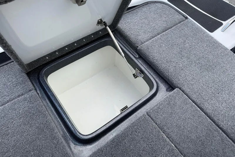 Slide: The Image of Open storage compartment in 2023 Phoenix 921 Elite II boat, featuring gray carpeted interior. - 19