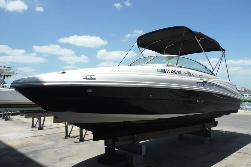 Slide: The Image of 2005 Sea Ray 220 Sundeck boat with canopy, docked under a clear blue sky. - 3