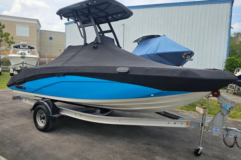 Slide: The Image of 2022 Yamaha Boats 190 FSH Sport, blue hull, covered, on trailer, outdoor storage. - 10
