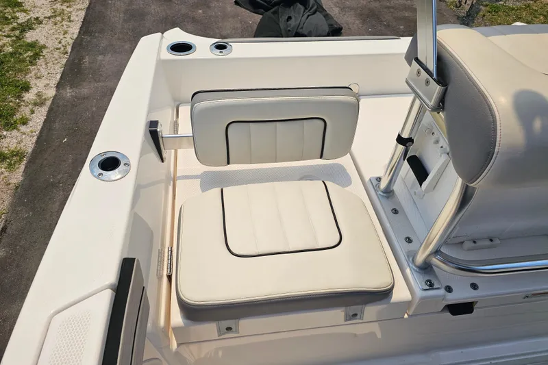 Slide: The Image of 2022 Yamaha Boats 190 FSH Sport interior seating with white cushioned seats and stainless steel fixtures. - 17
