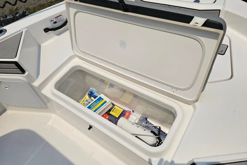 Slide: The Image of Open storage compartment on 2022 Yamaha Boats 190 FSH Sport, containing various boating supplies. - 21