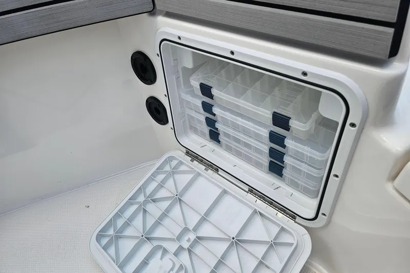 Slide: The Image of Storage compartment with tackle boxes on a 2022 Yamaha Boats 190 FSH Sport. - 27