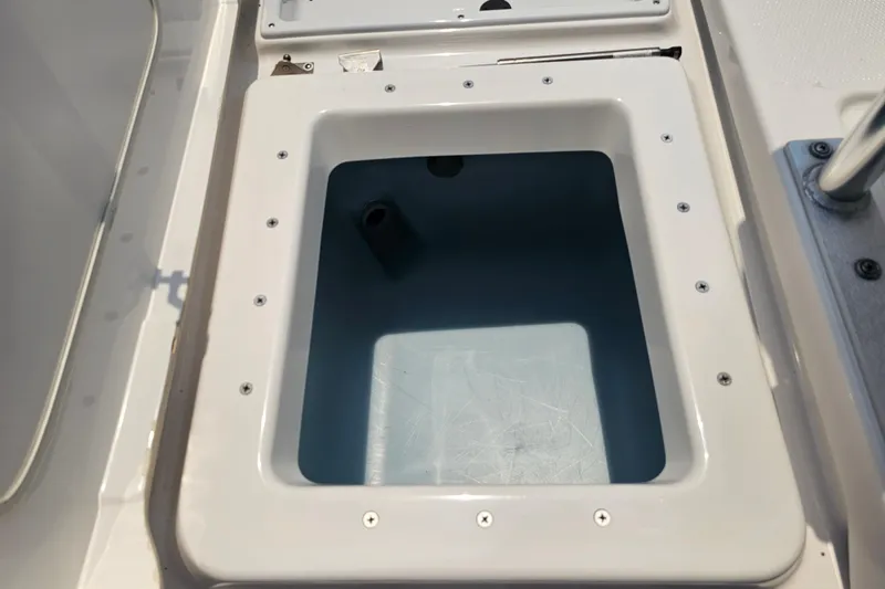 Slide: The Image of 2022 Yamaha Boats 190 FSH Sport storage compartment, open and empty, with visible screws and hinges. - 37