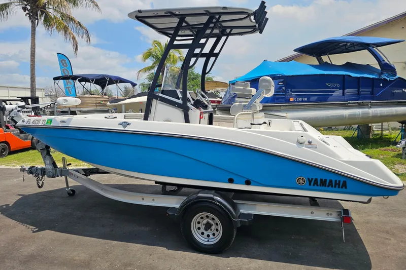 Slide: The Image of 2022 Yamaha Boats 190 FSH Sport in blue on trailer, parked outdoors. - 4