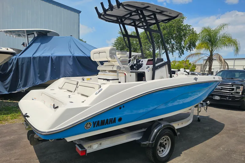 Slide: The Image of 2022 Yamaha Boats 190 FSH Sport in blue, parked on a trailer outdoors. - 6