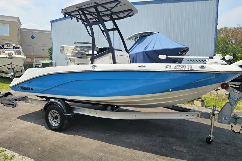 Slide: The Image of 2022 Yamaha Boats 190 FSH Sport in blue on trailer, parked outdoors. - 7