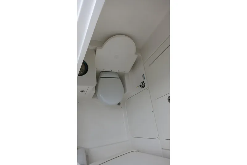 Slide: The Image of 2026 Robalo R300 Center Console boat interior with a compact marine toilet. - 14