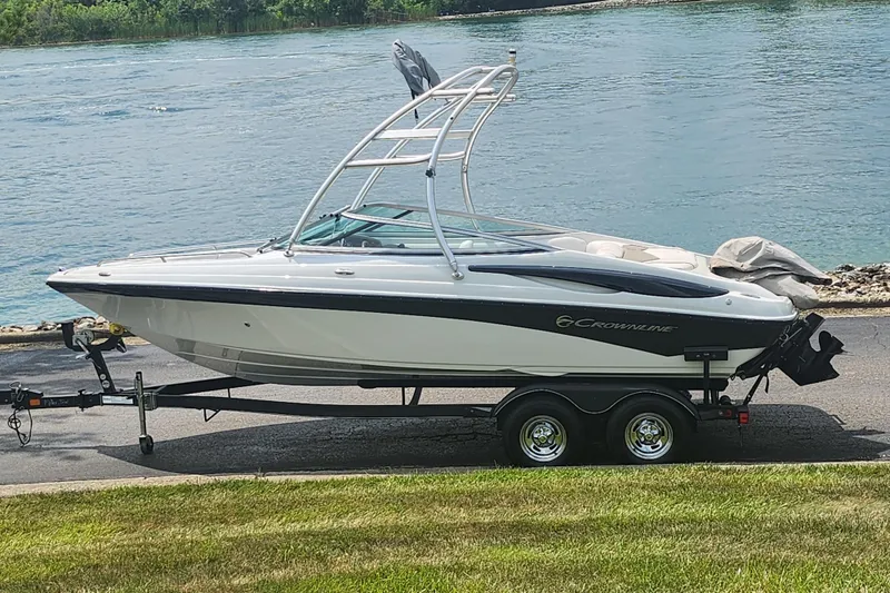 The Image of 2014 Crownline 21 SS boat on trailer by a riverbank. - 0