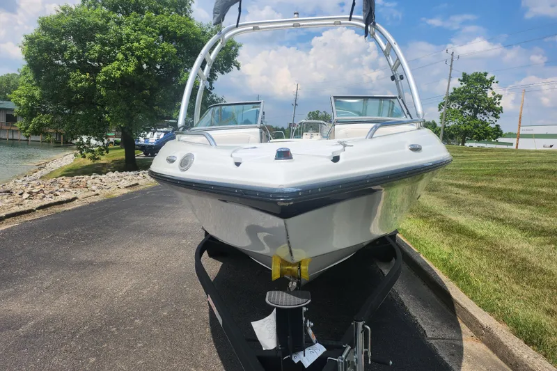 Slide: The Image of 2014 Crownline 21 SS boat on trailer, parked near a lake under a blue sky. - 6