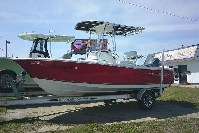 The Image of 2010 Sea Hunt Triton 202 boat on trailer, red hull, parked outdoors. - 0