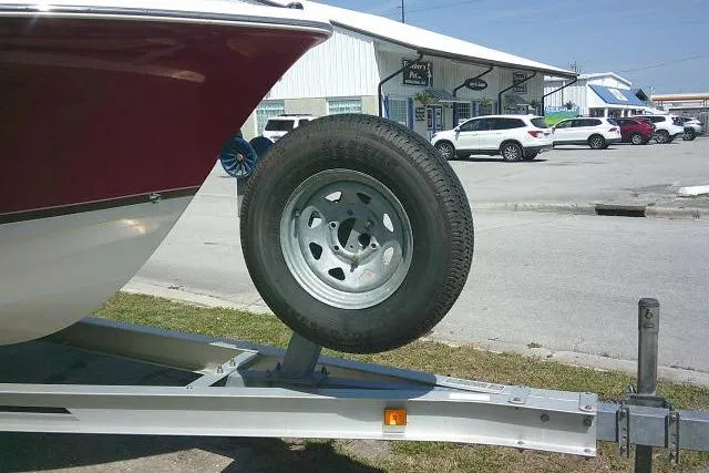 Slide: The Image of 2010 Sea Hunt Triton 202 boat on trailer with spare tire, parked near a building. - 9