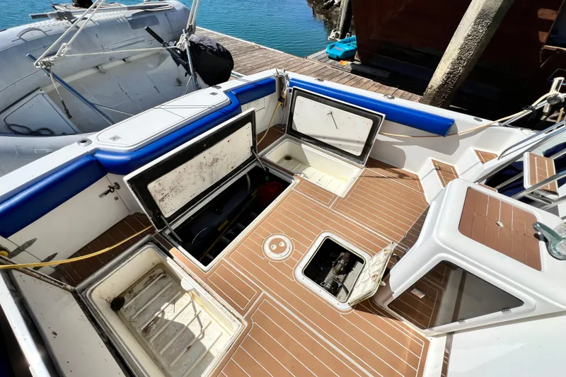 Slide: The Image of 1990 Mediterranean 38 Sport Fisher boat deck with open storage compartments, docked by the water. - 18