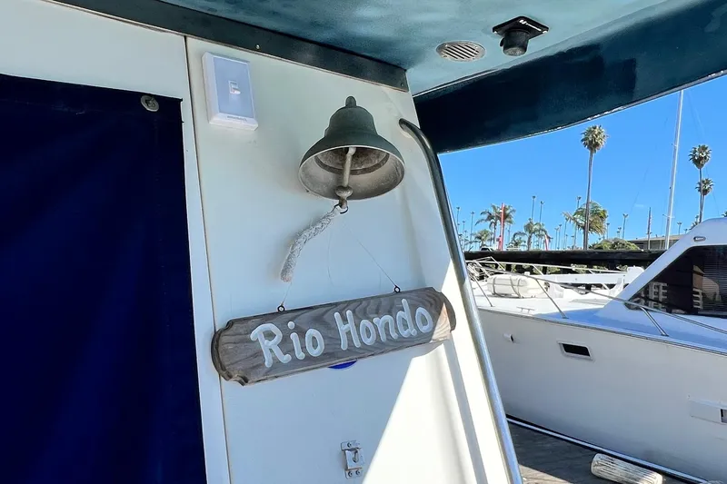 Slide: The Image of 1990 Mediterranean 38 Sport Fisher boat with 'Rio Hondo' sign and bell, docked under clear sky. - 19