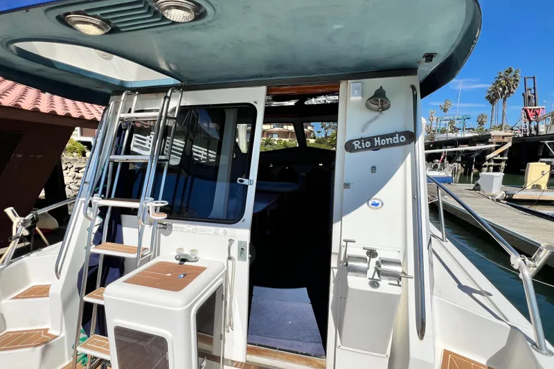 Slide: The Image of 1990 Mediterranean 38 Sport Fisher boat docked, featuring ladder and cabin entrance. - 34