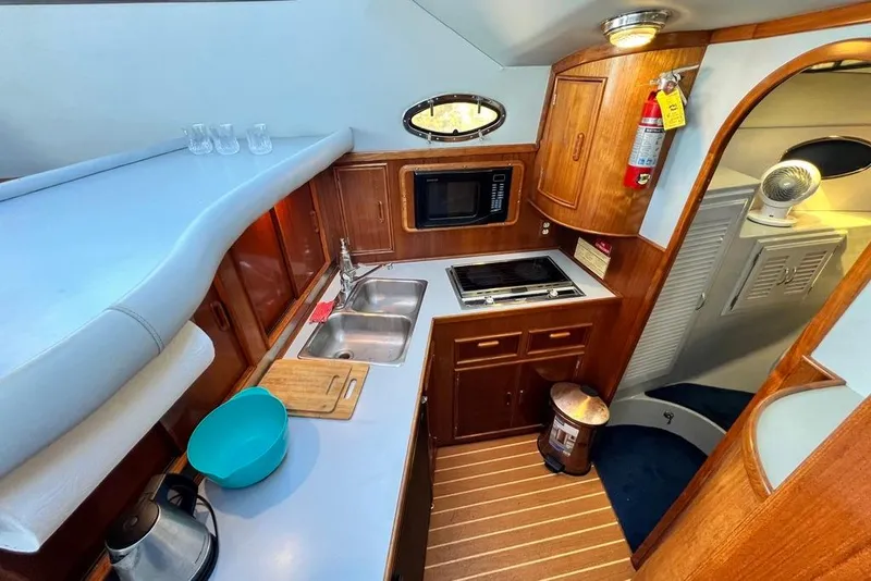 Slide: The Image of 1990 Mediterranean 38 Sport Fisher yacht kitchen with wooden cabinetry and modern appliances. - 38