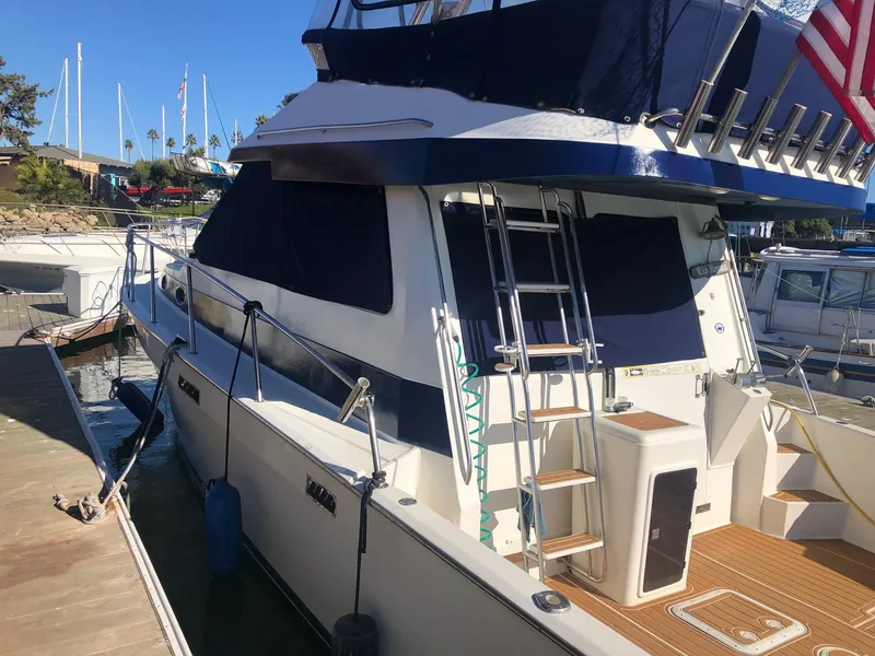 Slide: The Image of 1990 Mediterranean 38 Sport Fisher yacht docked, featuring blue and white design with ladder and American flag. - 5