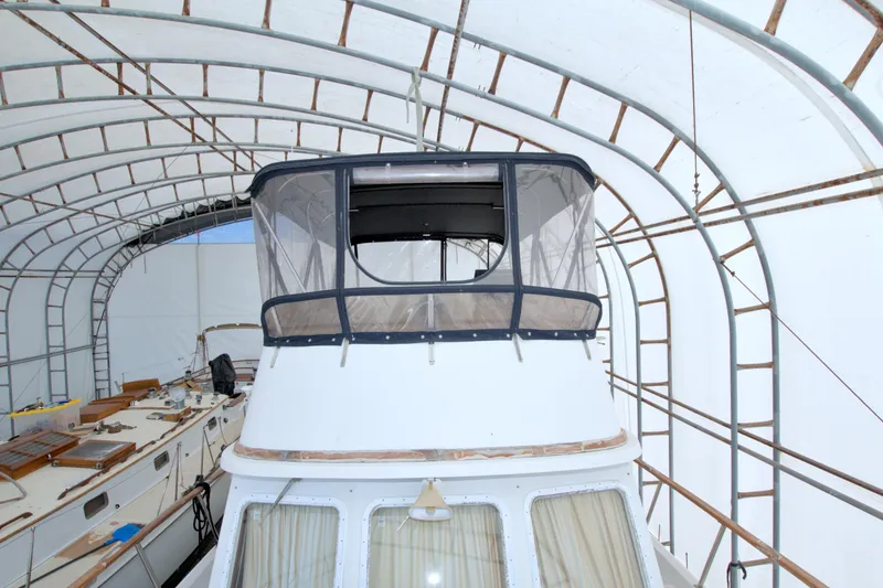 Slide: The Image of 1999 Monk 36 Trawler under protective shelter, showcasing upper deck and enclosed cockpit. - 14
