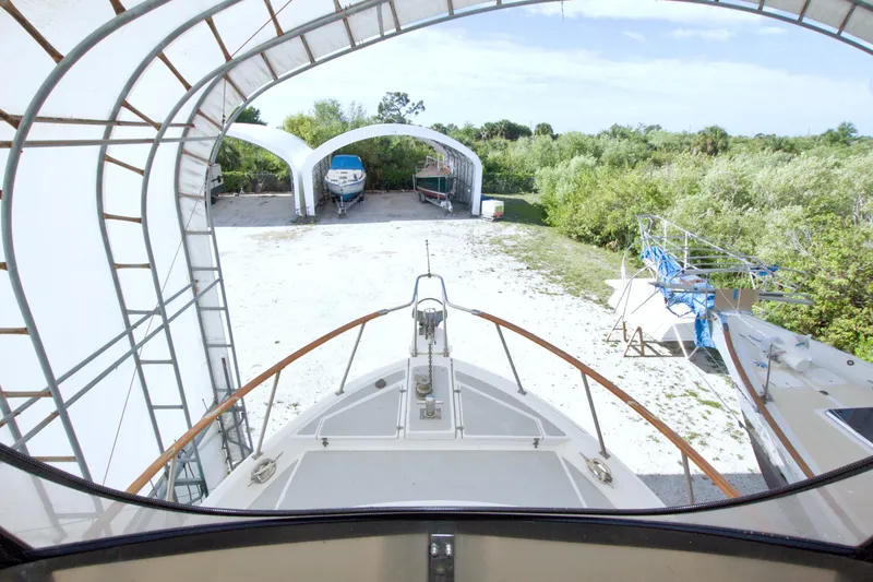 Slide: The Image of 1999 Monk 36 Trawler in covered storage, surrounded by greenery and other boats. - 23