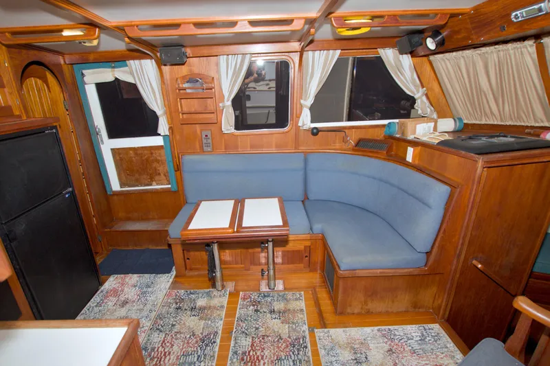 Slide: The Image of Cozy interior of a 1999 Monk 36 Trawler with blue seating and wooden accents. - 30