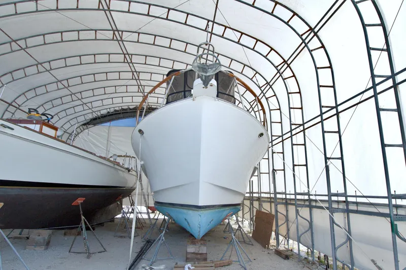 Slide: The Image of 1999 Monk 36 Trawler in covered storage, showcasing its hull and structure. - 4