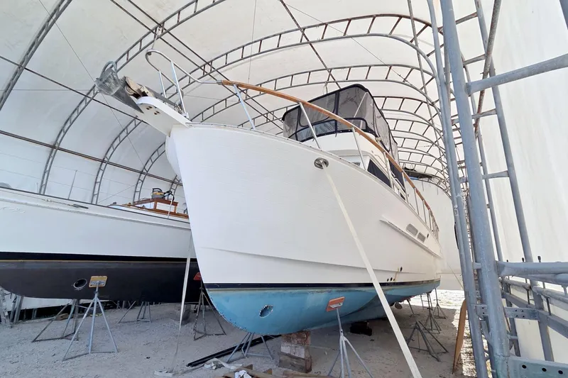 Slide: The Image of 1999 Monk 36 Trawler in dry dock, covered, with visible hull and scaffolding. - 5