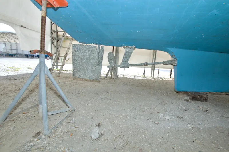 Slide: The Image of Underneath view of a 1999 Monk 36 Trawler on dry dock, showing propeller and rudder. - 73