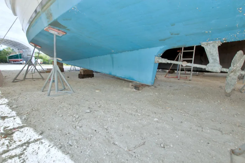 Slide: The Image of 1999 Monk 36 Trawler on dry dock, supported by stands, showing blue hull and propeller. - 77