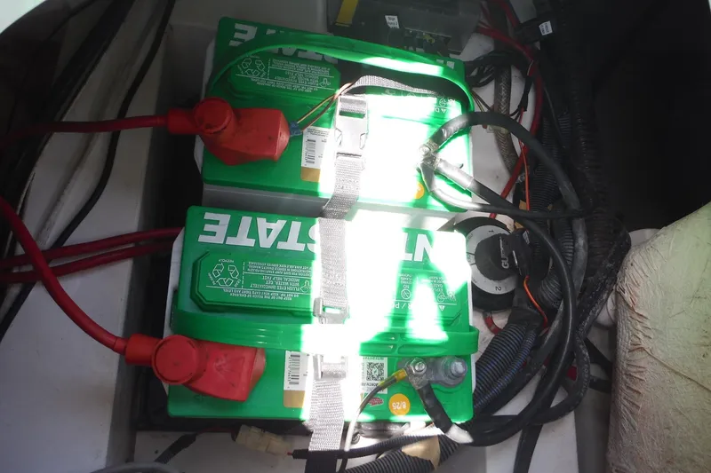 Slide: The Image of 2018 Hurricane SunDeck 2690 OB boat battery compartment with dual green batteries and wiring. - 18