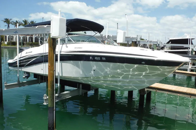Slide: The Image of 2018 Hurricane SunDeck 2690 OB boat docked on a lift in a marina. - 2