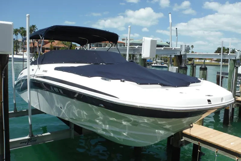 Slide: The Image of 2018 Hurricane SunDeck 2690 OB boat docked with cover on, under sunny skies. - 33