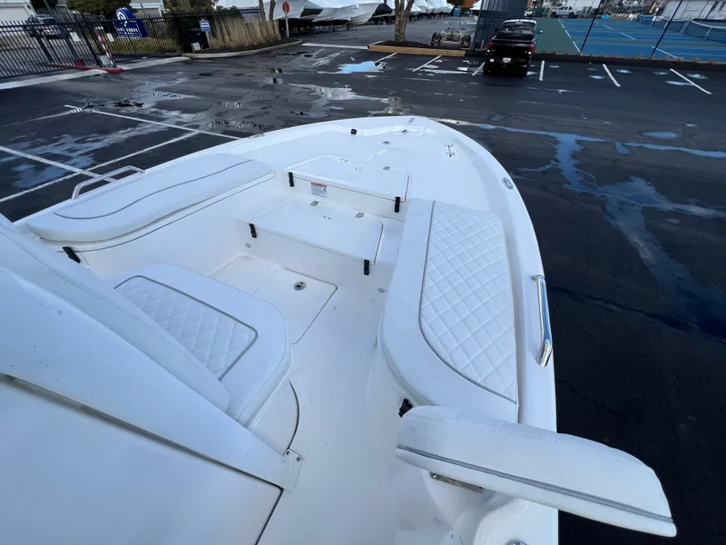 Slide: The Image of 2024 Sea Fox 231 Bay Fox boat with white cushioned seating in a parking lot. - 30