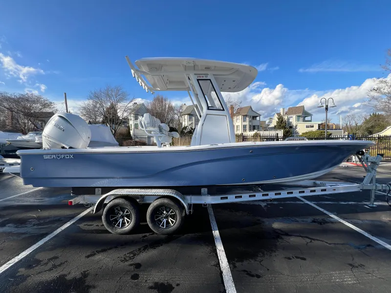 The Image of 2024 Sea Fox 251 Bay Fox boat on trailer, parked outdoors under blue sky. - 0