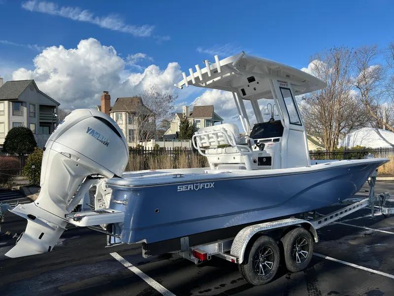 Slide: The Image of 2024 Sea Fox 251 Bay Fox boat with Yamaha engine on trailer, parked outdoors. - 2