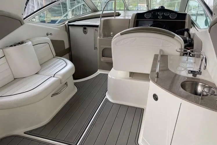 Slide: The Image of 2006 Sea Ray 290 Sundancer interior with seating, helm, and kitchenette. - 12