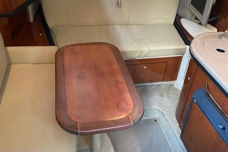 Slide: The Image of Interior of a 2006 Sea Ray 290 Sundancer with a wooden table and beige seating. - 37