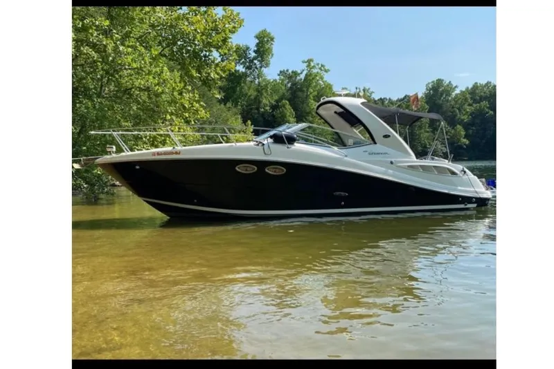 Slide: The Image of 2006 Sea Ray 290 Sundancer boat on calm water, surrounded by lush greenery. - 6