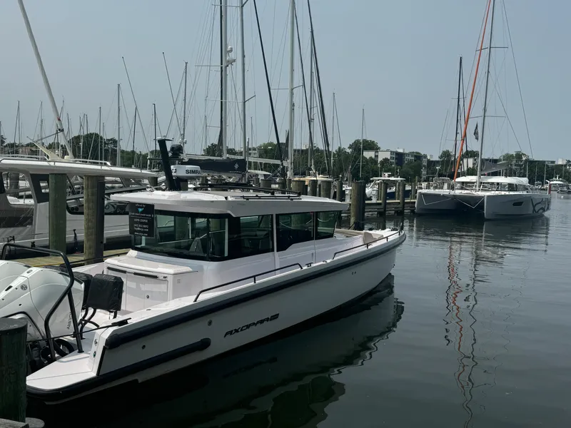 Slide: The Image of 2024 Axopar 37 Cross Cabin XC docked in a marina with sailboats. - 2