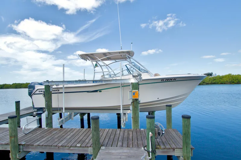 The Image of 2013 Grady-White Freedom 275 boat docked on a lift by a serene lake. - 0