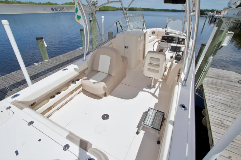 Slide: The Image of 2013 Grady-White Freedom 275 boat interior, featuring spacious seating and helm, docked by the water. - 10