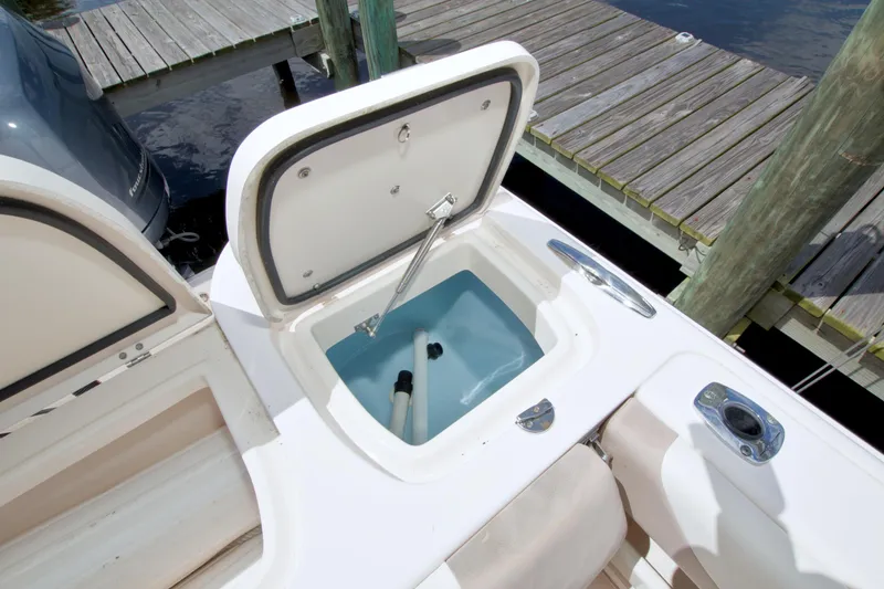 Slide: The Image of Open storage compartment on 2013 Grady-White Freedom 275 boat by a dock. - 16