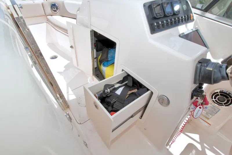 Slide: The Image of 2013 Grady-White Freedom 275 boat interior with open storage compartments and control panel. - 24