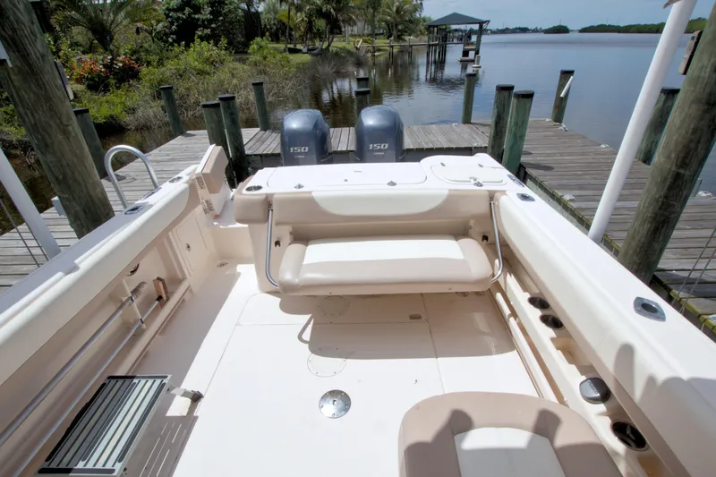 Slide: The Image of 2013 Grady-White Freedom 275 boat interior with dual engines, docked by a scenic waterfront. - 36