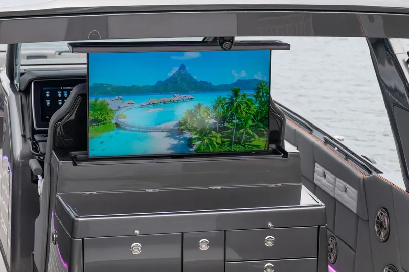 Slide: The Image of 2025 Cigarette 42' Auroris yacht with a retractable screen displaying a tropical island scene. - 9