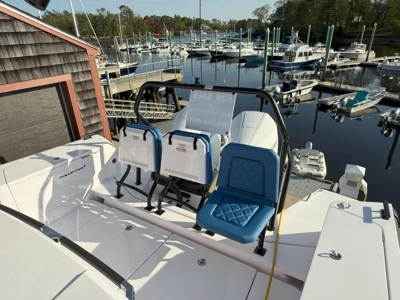 Slide: The Image of 2024 Axopar Cross Cabin boat docked at marina with seating and scenic water view. - 10