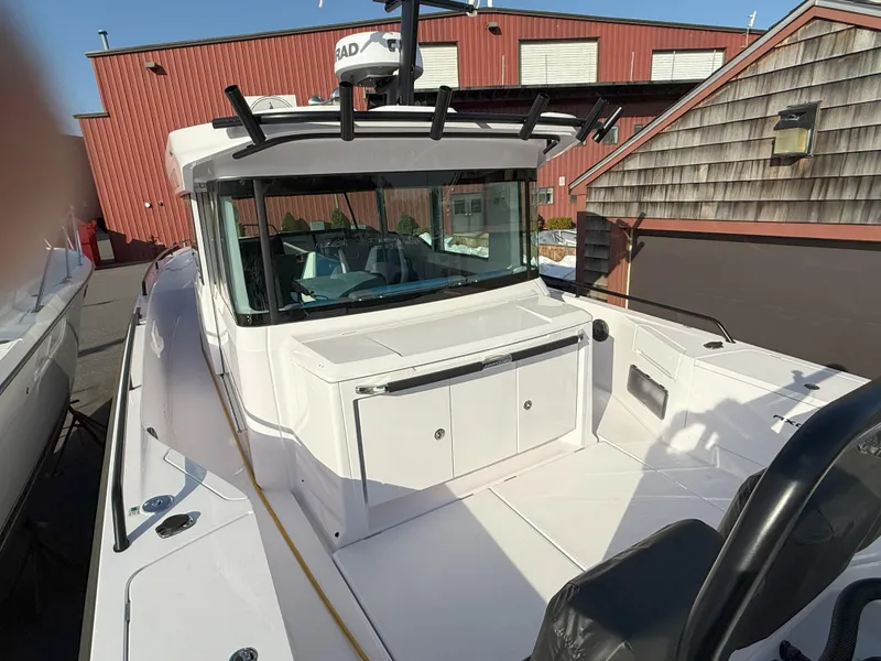 Slide: The Image of 2024 Axopar Cross Cabin boat with sleek design, docked near red building. - 12