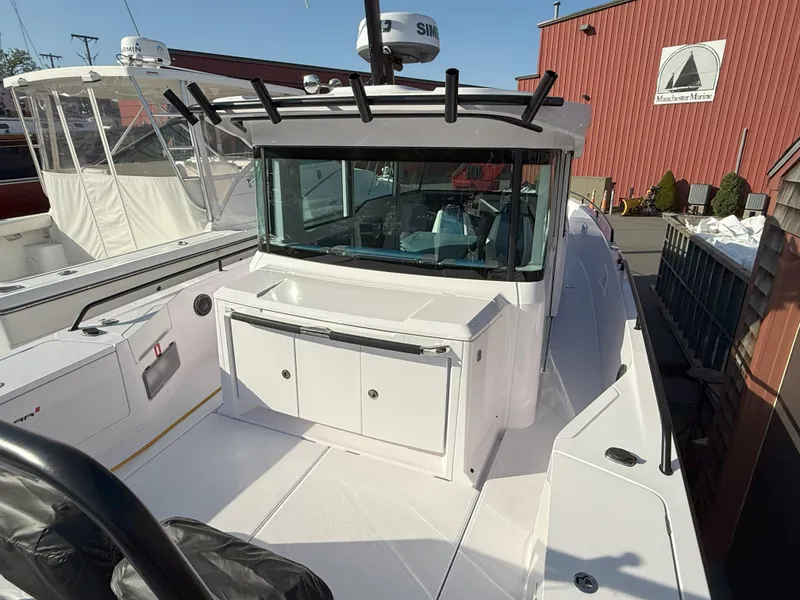 Slide: The Image of 2024 Axopar Cross Cabin boat with sleek design, docked near a red building. - 13