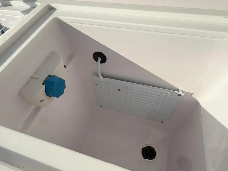 Slide: The Image of 2024 Axopar Cross Cabin storage compartment with drainage and blue valve. - 16